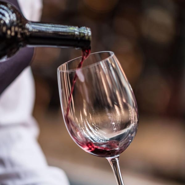 Red wine pouring from a bottle into a clear wine glass at a bistro.